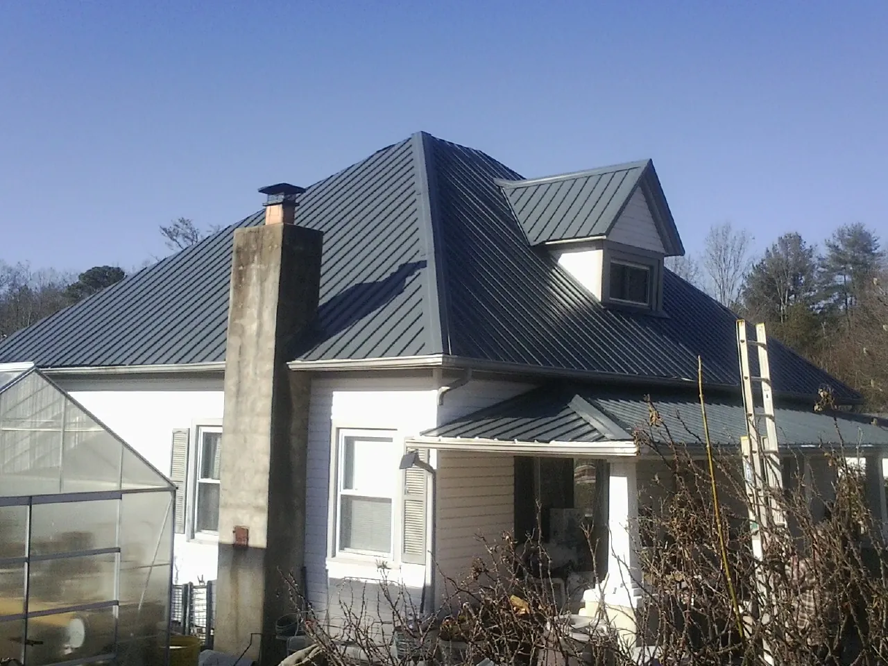 Dark blue standing seam metal roof on a white farmhouse with dormer — Slate & Tile Roof Repair by Roofing Brothers in Port Royal