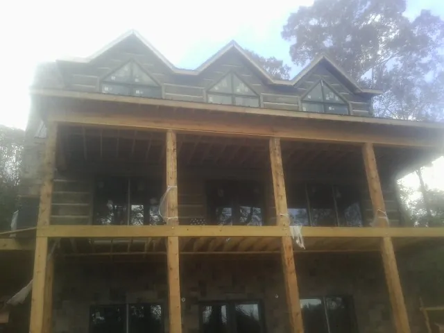 Dormers and porch framing on a large log home under construction — Roof Coating work by our crew in Port Royal