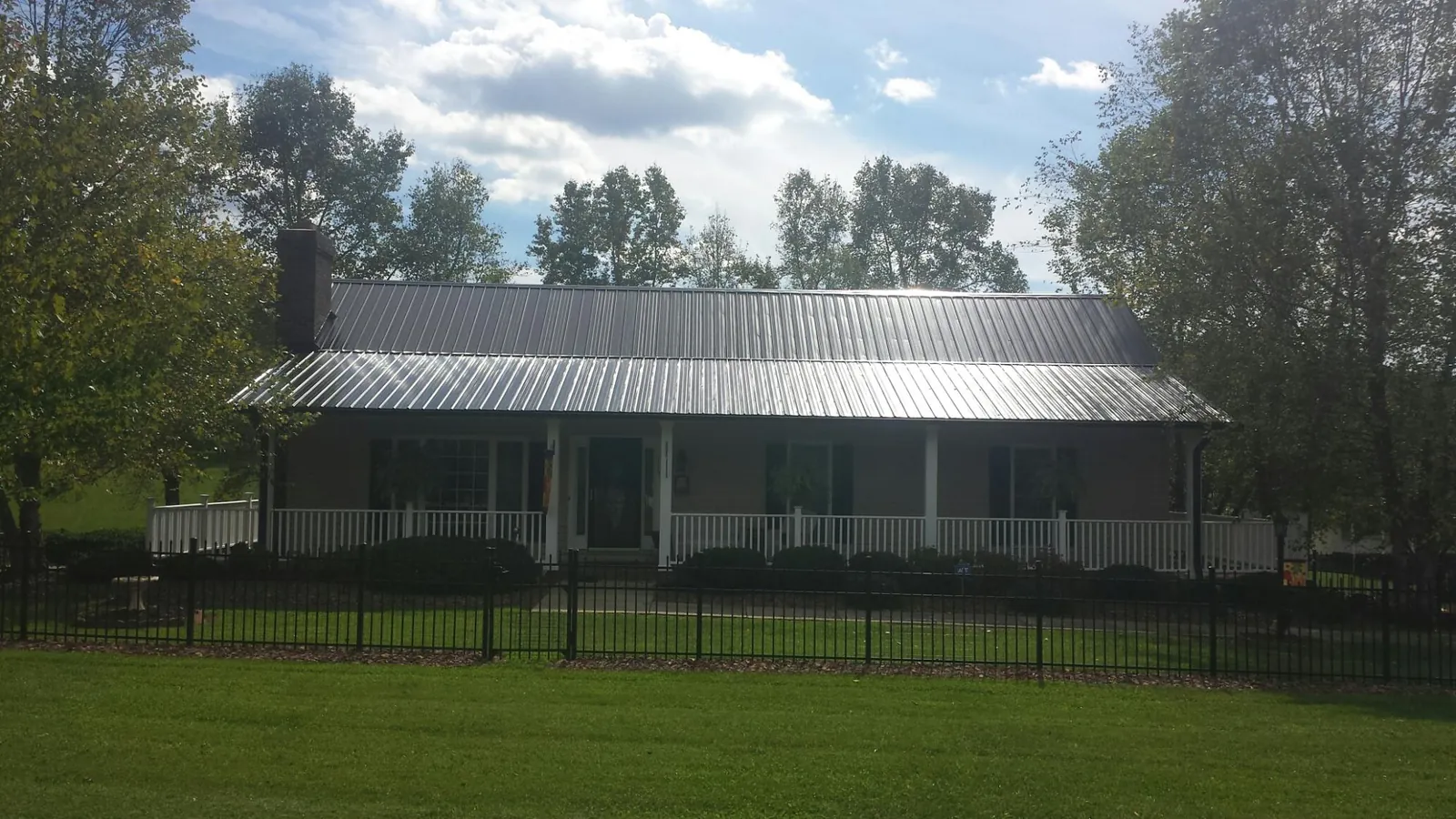 Gray metal roof on a brick ranch with a full width front porch — Gutter Guard Installation work by our crew in Port Royal